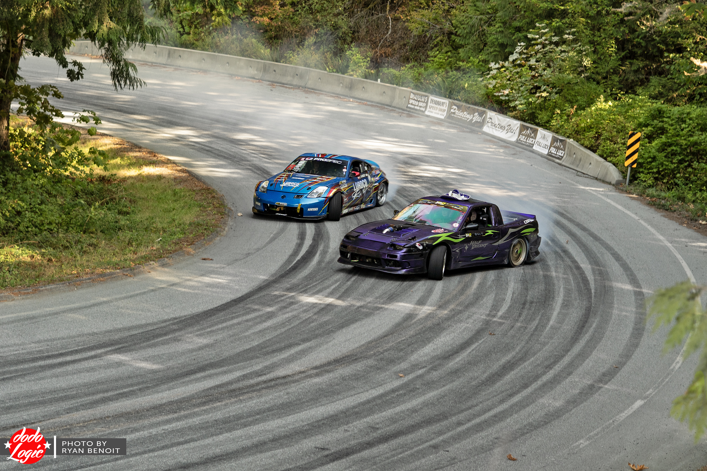 Blue and purple drift cars run together through a mountain hairpin