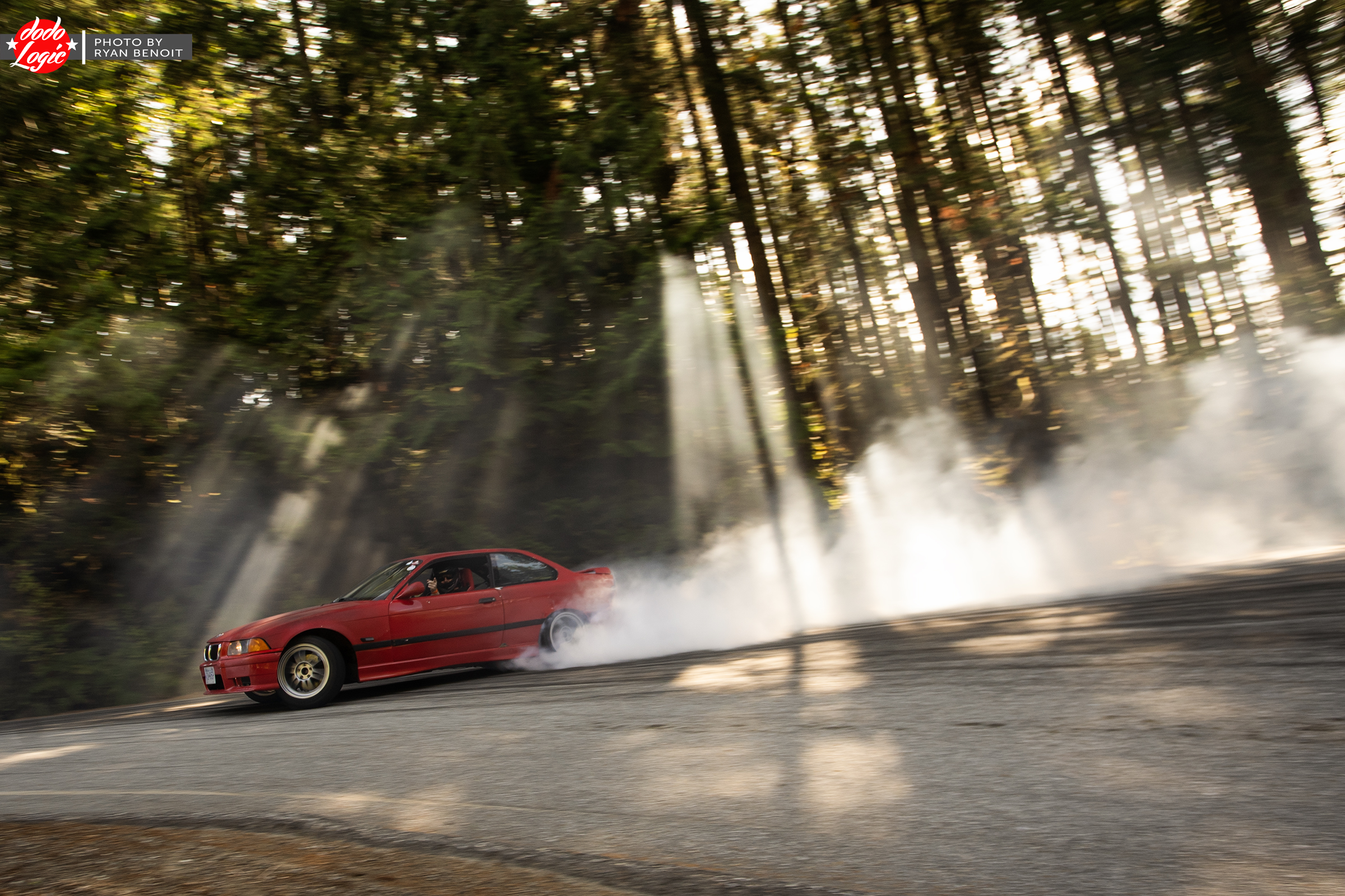 Red drift car passes through shafts of sunlight and smoke in the forest